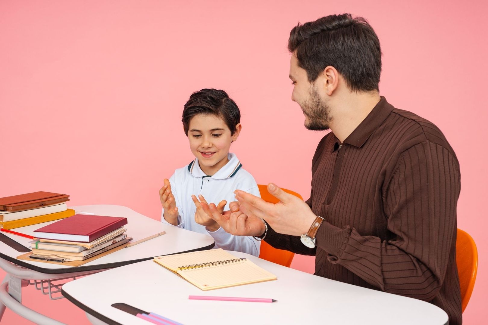 Ouder en kind bespreken schoolwerk aan tafel met boeken en notitieblok