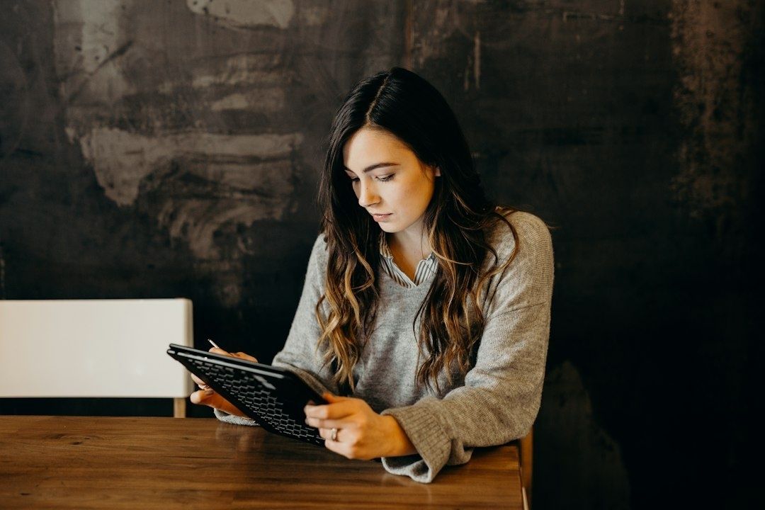 Jonge vrouw gebruikt een tablet aan een houten tafel