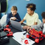 Drie leerlingen werken samen met een laptop en technische apparaten