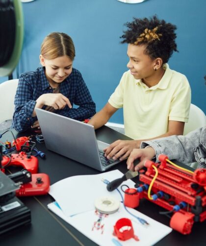 Drie leerlingen werken samen met een laptop en technische apparaten