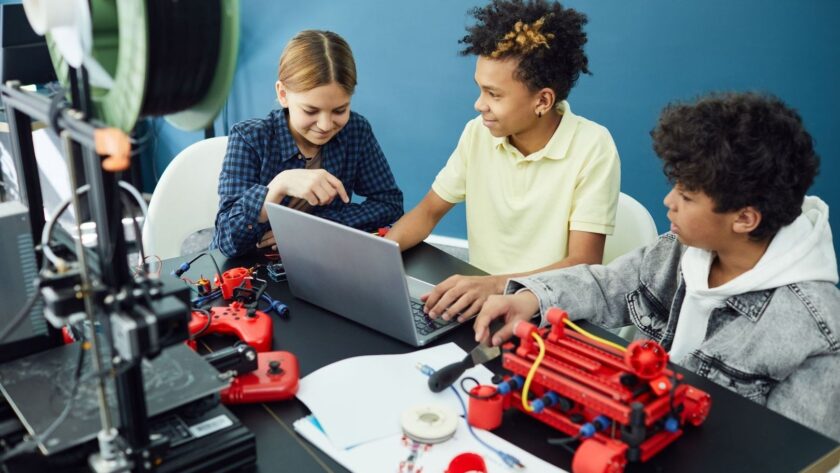 Drie leerlingen werken samen met een laptop en technische apparaten
